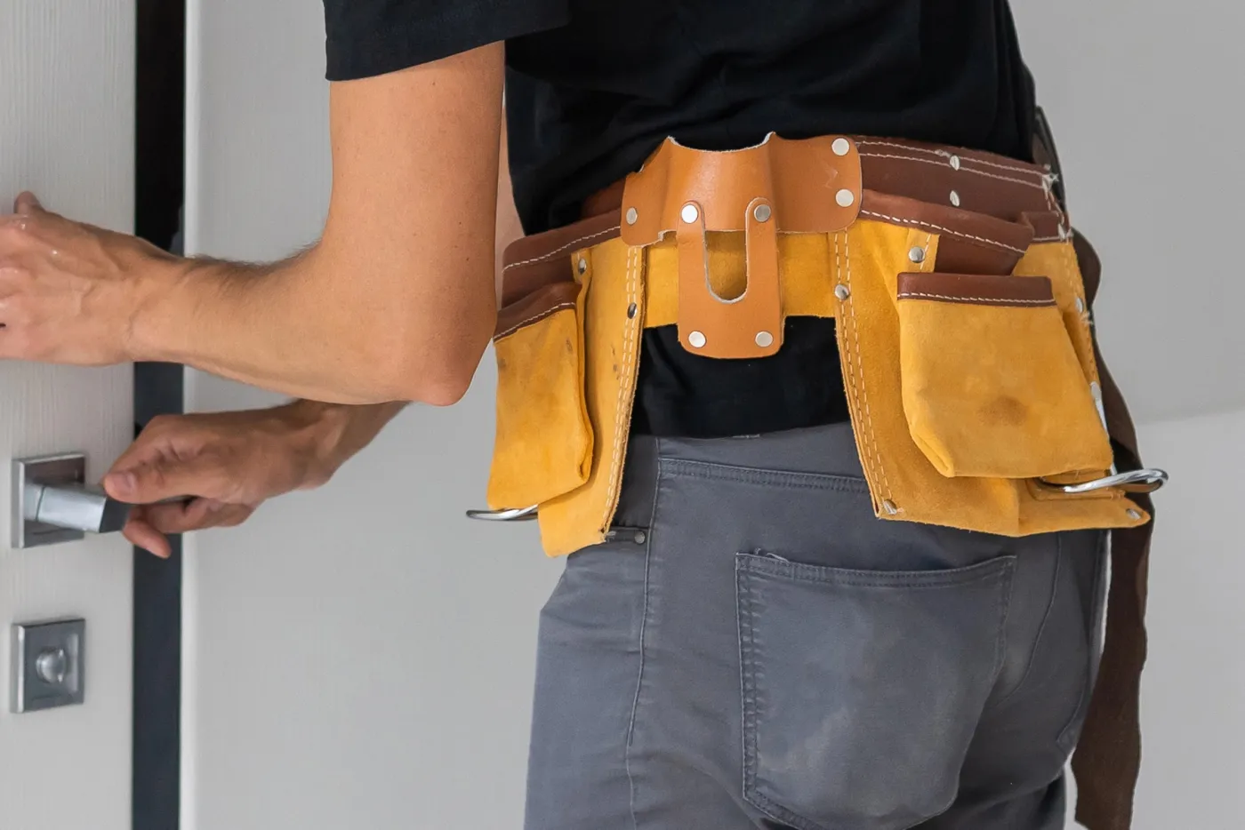 Artisan serrurier en ceinture à outils ouvrant une porte d'appartement à Montrouge (92120)